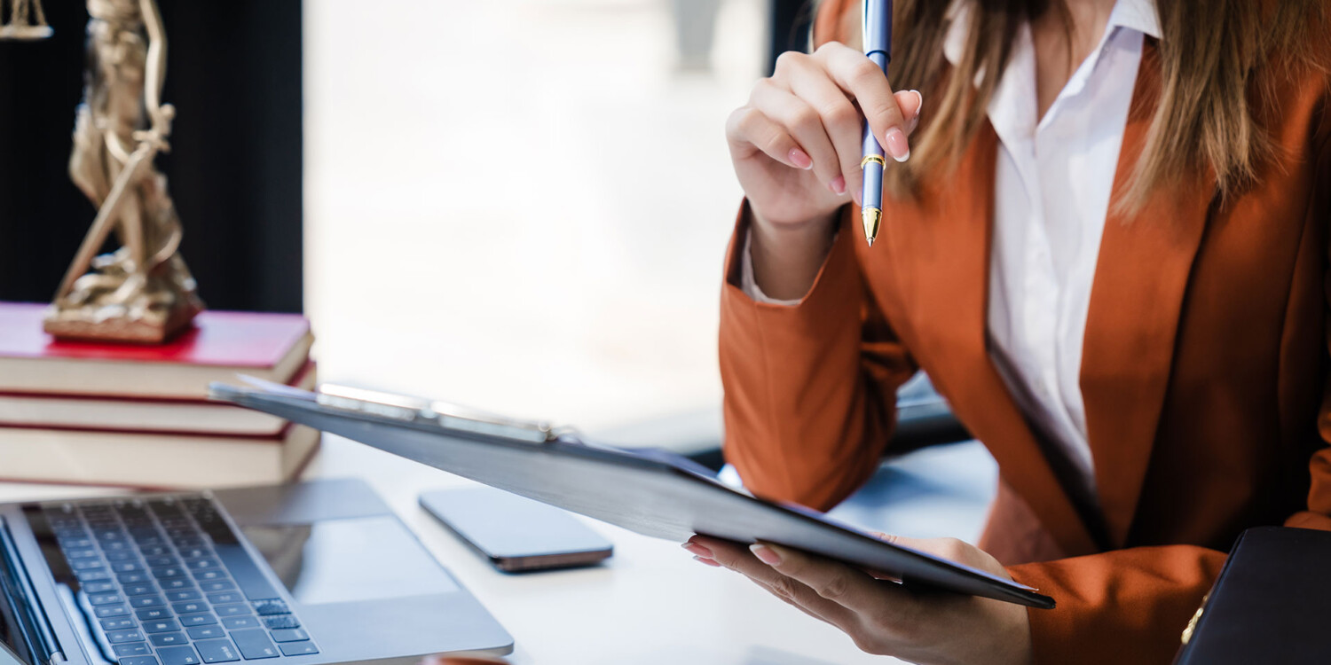Advogada analisando documentos em tablet durante assessoria a empresa