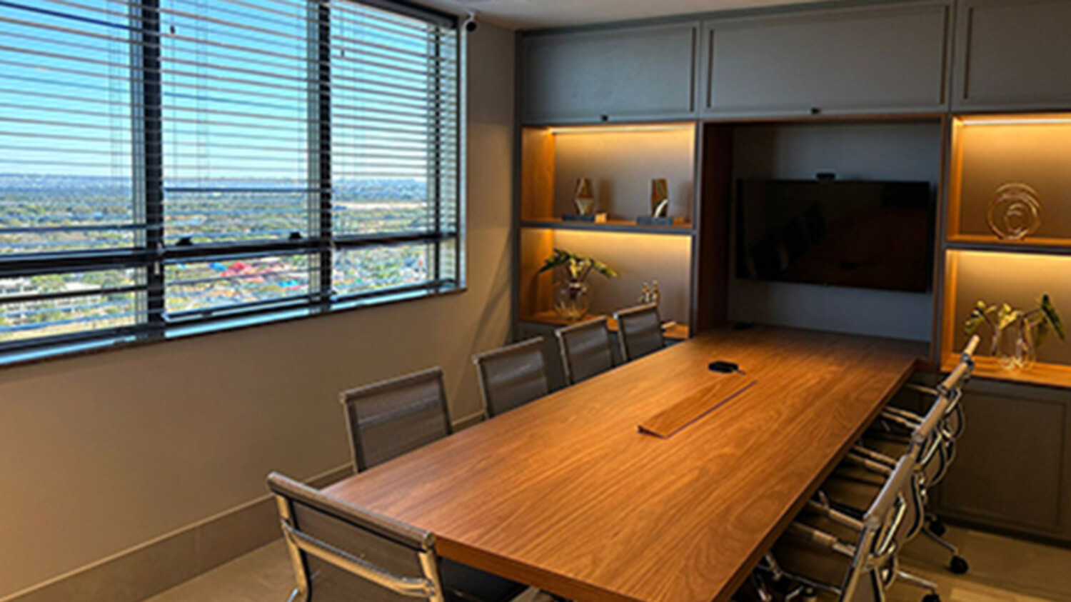 Sala de reuniões da unidade de Brasília, com mesa de madeira e vista da cidade pela janela