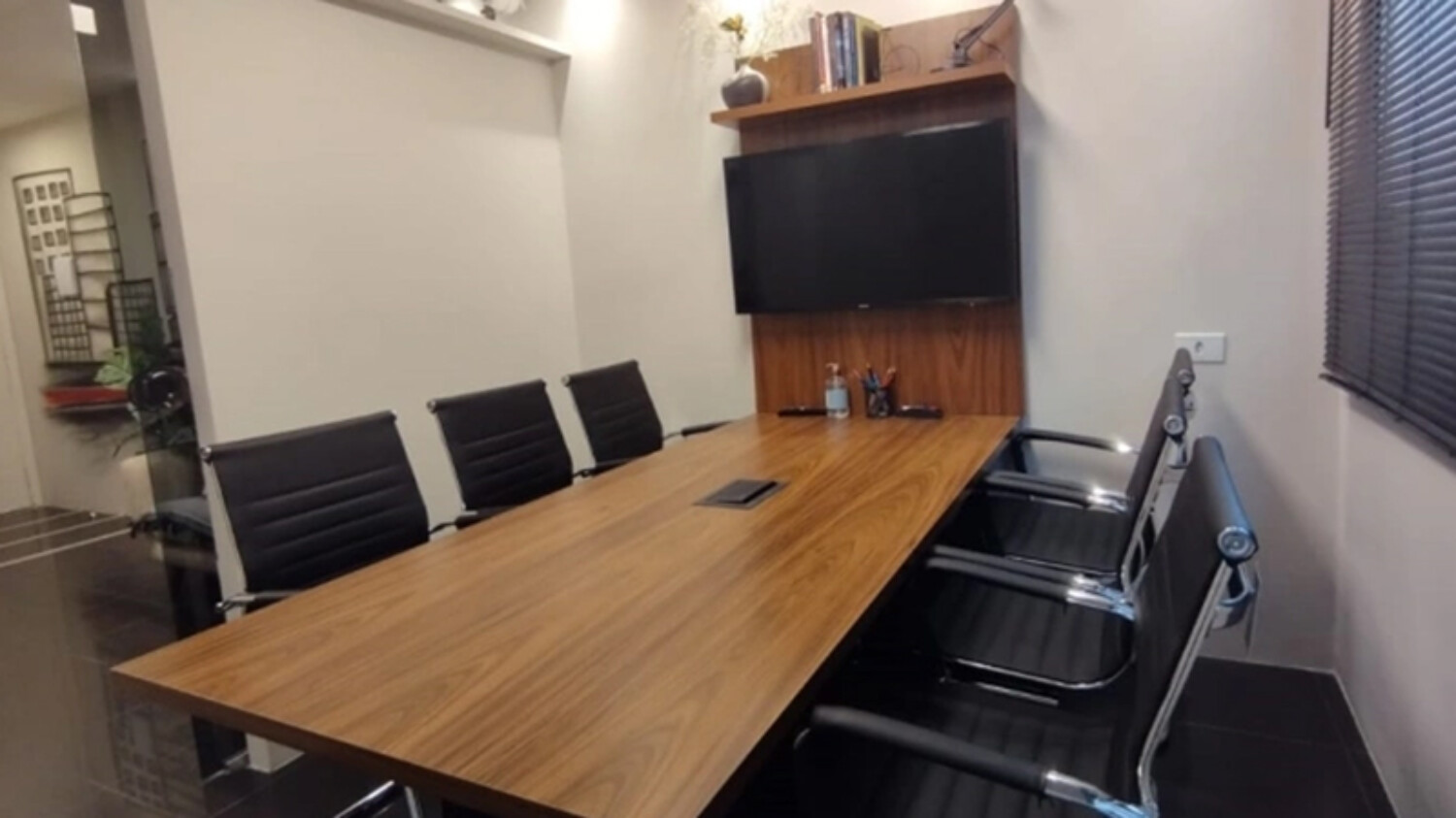Sala de reuniões da unidade de São Paulo, com mesa de madeira e painel de vídeo