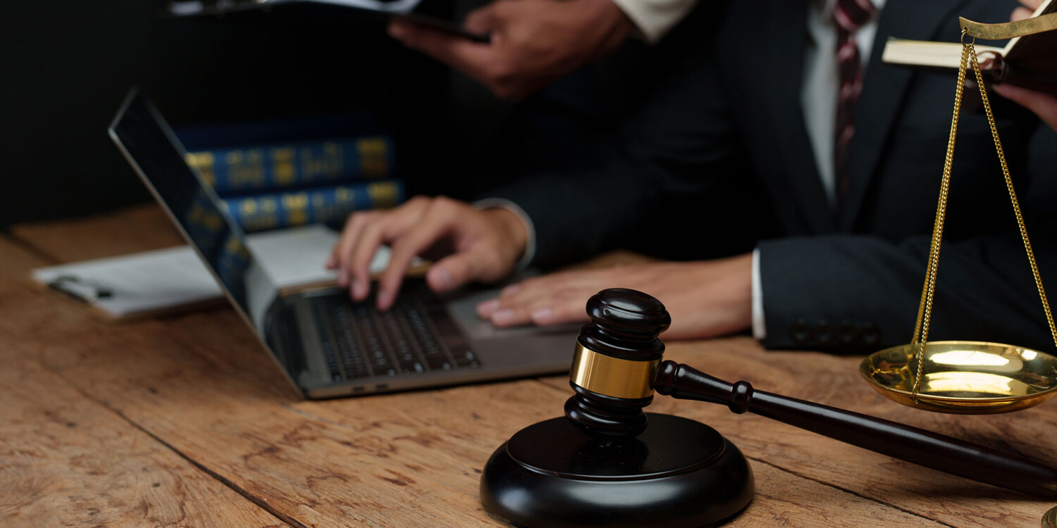 Advogados trabalhando com martelo de juiz e balança da justiça sobre a mesa