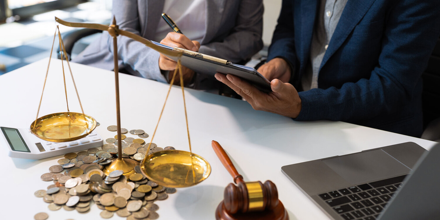 Balança com moedas e martelo de juiz ao lado de notebook