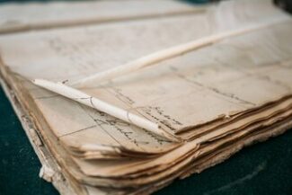 Cidadania Italiana e Portuguesa Documentos antigos manuscritos empilhados, simbolizando pesquisa genealógica para reconhecimento de cidadania