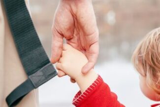 Mão de adulto segurando a mão de uma criança, simbolizando cuidado e responsabilidade parental