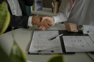 Aperto de mãos sobre documento assinado, representando acordo de remuneração e direitos funcionais
