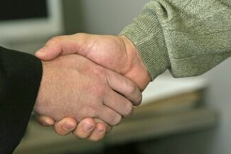 Aperto de mãos em ambiente corporativo, simbolizando a formalização de rescisão de contrato de trabalho