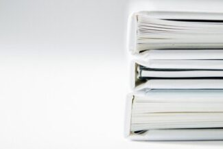 Pilha de pastas e documentos organizados, representando gestão de processos administrativos