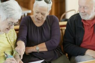 Três pessoas idosas revisando documento juntas, representando questões de aposentadoria