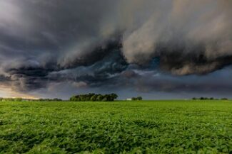 Nuvens de tempestade sobre plantação verde, representando os riscos cobertos pelo seguro rural