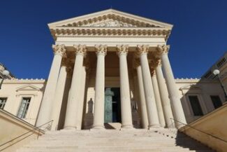 Fachada neoclássica de tribunal com colunas e escadaria