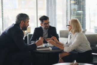 Profissionais em reunião analisando documentos em ambiente corporativo, representando contratos administrativos