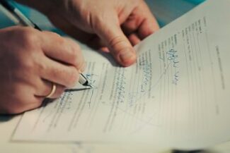 Contratos Bancários Assinatura de documento com caneta sobre a mesa, representando contratos bancários