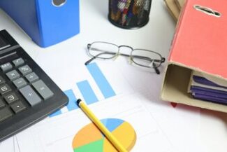 Mesa de escritório com calculadora, gráficos e pastas, representando planejamento e gestão jurídica
