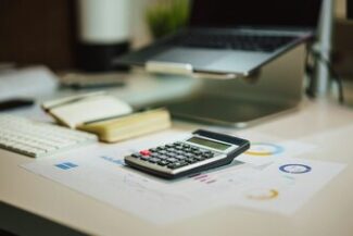 Mesa de trabalho com calculadora e relatórios, representando planejamento tributário