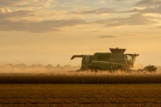 Colheitadeira em operação ao entardecer, representando a atividade produtiva rural