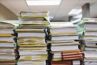 Pilhas de processos em papel empilhadas sobre mesa de escritório