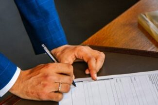 Homem de terno preenche formulário sobre mesa de escritório